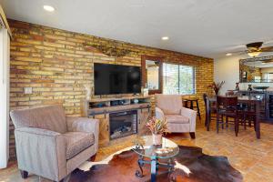 a living room with a brick wall with a fireplace and a tv at Tranquil Trail #6 in Carefree