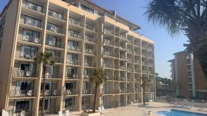 a large building with palm trees and a swimming pool at Atlantic Crest Inn and Suites in Myrtle Beach