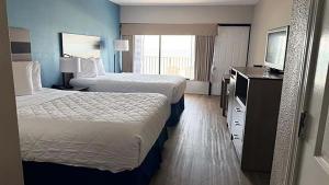 a hotel room with two beds and a flat screen tv at Atlantic Crest Inn and Suites in Myrtle Beach