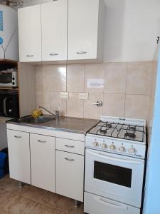 a kitchen with a stove and white cabinets at Espacio Pueyrredón in Comodoro Rivadavia