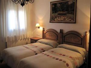 two beds in a hotel room with a window at La Ventana De Tejera Negra in Cantalojas