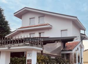 a white house with a balcony on top of it at Foresteria Tosi in San Colombano al Lambro