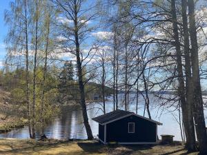 a small blue house sitting next to a body of water at Lappnäs Bed & Breakfast in Sunne