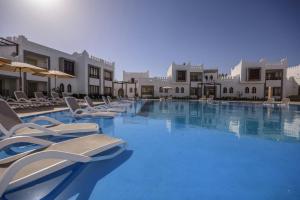 a large swimming pool with lounge chairs and umbrellas at Mazar Resort & Spa in Sharm El Sheikh