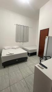a room with two beds and a television in it at Pousada Só Alegria in Fortaleza
