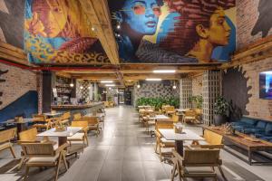 a restaurant with tables and chairs and a mural at Hotel Zelva Negra in Medellín