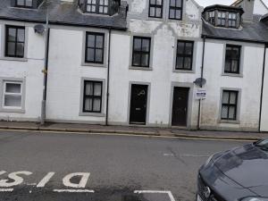 a white building with black doors on a street at Little Nuek in Largs