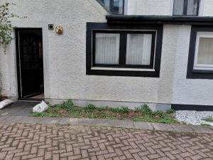 a cat is sitting outside of a house at Little Nuek in Largs +5 photos