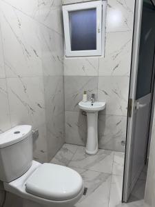 a white bathroom with a toilet and a sink at Guesthouse Natyra Theth in Theth