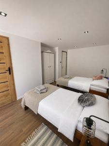 two beds in a room with white walls and wooden floors at Leśny Dworek Marianny 4 osobowy in Miedzygorze