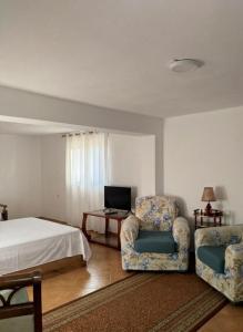 a bedroom with two chairs and a bed and a television at Guest house Irvin in Berat