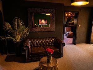 a living room with a brown leather couch and a table at Emotion Apartments- BDSM Apartment mit privater Sauna in Vlotho