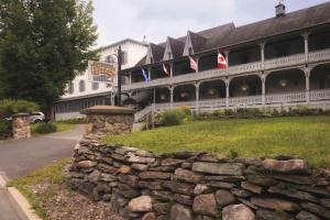 a stone wall in front of a building with flags at Auberge Lakeview Inn in Lac-Brome