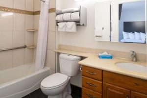 a bathroom with a toilet and a sink and a tub at Sand Castle Inn in Seaside +20 photos