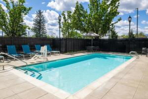 a swimming pool with blue chairs and a fence at TownePlace Suites Redding in Redding
