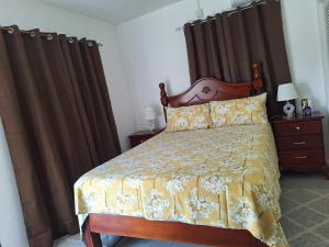 a bedroom with a bed with a yellow comforter and curtains at 14 Zeneith Avenue in Harbour View