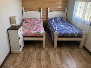 a bedroom with two beds and a night stand with a bedskirts at Las andinas in Carmelo