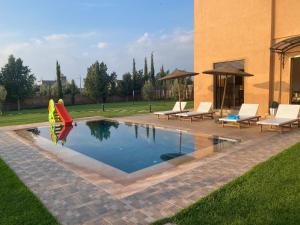 a swimming pool with chairs and a playground at Villa Dar Daraa with Pool in Najem
