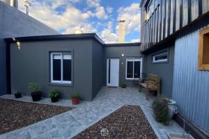 a gray house with a patio with potted plants at SH Aparts Depto 1 in Coronel Suárez