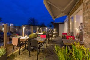 an outdoor patio with tables and chairs at night at Hotel Duinlust in Domburg