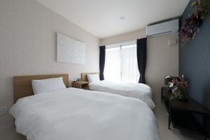 a hotel room with two beds and a window at Beppu ZEN in Beppu