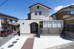 a white house with a gate in front of it at Beppu ZEN in Beppu
