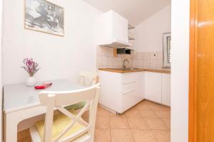 a white kitchen with a table and a sink at Apartments Mir in Duće