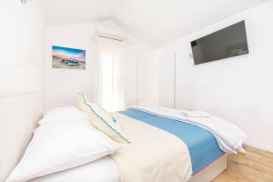 a white bedroom with a bed and a flat screen tv at Apartments Mir in Duće