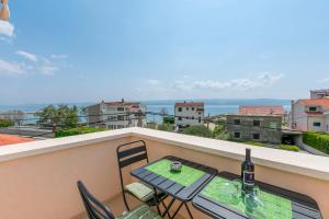 a table and chairs on a balcony with a bottle of wine at Apartments Mir in Duće +76 photos