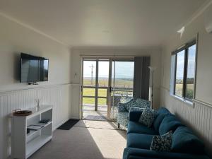 a living room with a blue couch and a tv at Prom Gate Getaway in Yanakie