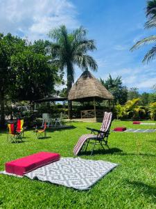 a group of chairs sitting in the grass with a gazebo at St. Patrick’s Forest House in Entebbe