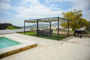 a pavilion with a table and a grill on a patio at Finca Tres Aguas, Casa Rural con Piscina Privada in Lanjarón