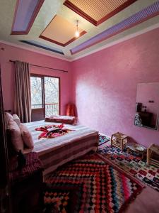 a bedroom with pink walls and a bed and a rug at imlil in Imlil