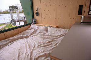 an empty bed in a room with a window at Tiny House Nook 1 - Green&Tiny Hideaway Eider in Süderstapel