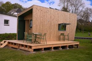 a tiny house with a table and chairs on a deck at Tiny House Nook 1 - Green&Tiny Hideaway Eider in Süderstapel