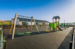 an empty playground with swings and a slide at Aurora Beacon View in Lossiemouth