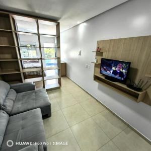 a living room with a couch and a tv on a wall at Apt 08, aconchegante e prático, para sua estadia in Igrejinha