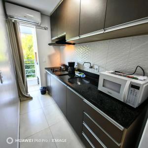 a kitchen with a sink and a microwave on a counter at Apt 08, aconchegante e prático, para sua estadia in Igrejinha