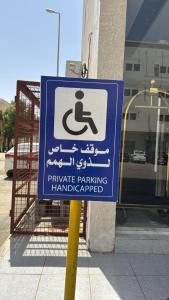 a blue and white sign on a pole next to a building at شقق زهرة النزلاء المخدومة الخرج in Al Kharj