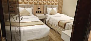 a hotel room with two beds with white sheets at السناء للشقق المخدومة Alsanaa in Jeddah