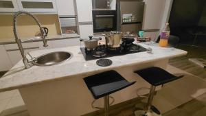 a kitchen with a sink and a counter with two stools at Hyponia 1512 in Oshikuku +2 photos