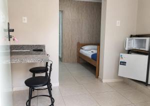 a room with a kitchen with a counter and a bed at Loft aconchegante Champagnat 1136 in Poços de Caldas