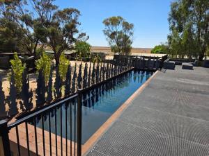 a swimming pool with a black fence and trees at Kangaroo Lake C & V Park in Mystic Park