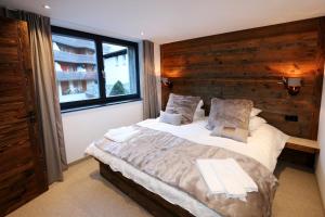 1 dormitorio con 1 cama grande y pared de madera en Heinrida en Saas-Fee