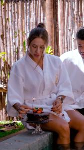 a woman sitting on a table with a cake with a candle at VILA GAHERI Pousada Boutique com Piscina Privativa in São Miguel dos Milagres +69 photos
