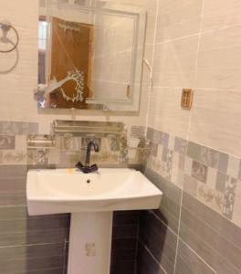 a bathroom with a white sink and a mirror at Sapphire Guest House in Karachi