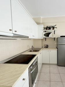a kitchen with white cabinets and a sink at Agapidis Apartment in Hanioti +15 photos