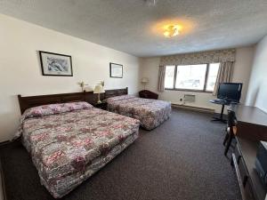 a hotel room with two beds and a television at Auberge Eldo Inn in Blind River
