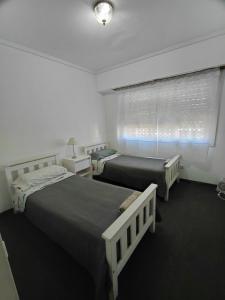 two beds in a white room with a window at Danny ap - Amplio y cómodo - 18 min Aeropuerto - Zona de Restos - Parking in Monte Grande
