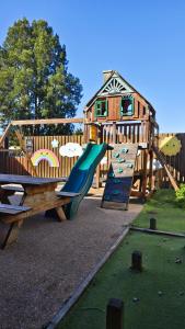 a wooden playground with a slide and a building at Alexandra Hotel in Pirongia